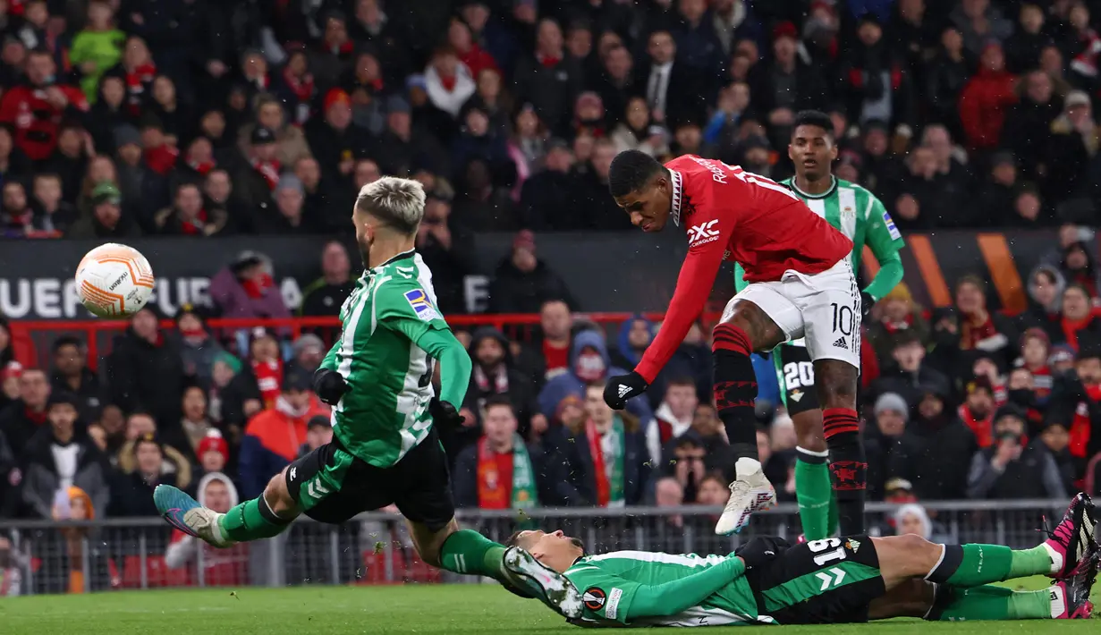 Striker Manchester United, Marcus Rashford melepaskan tendangan yang menghasilkan gol ke gawang Real Betis pada laga leg pertama babak 16 besar Liga Europa 2022/2023 di Old Trafford Stadium, Manchester (9/3/2023). Marcus Rashford menjadi top skor MU dalam 5 edisi Liga Europa yang diikutinya. Ia total telah mencetak 13 gol dan 9 assist dalam 35 penampilan. (AFP/Darren Staples)
