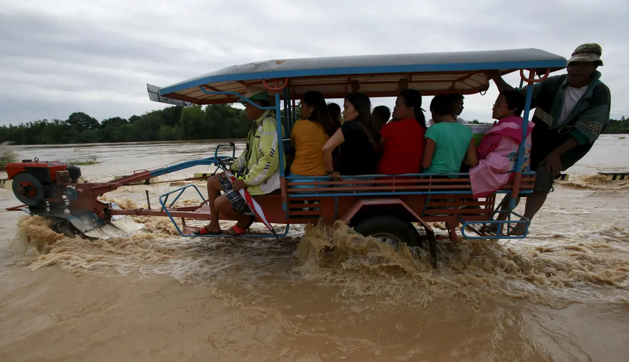 Warga Filipina mengunakan traktor menyebrangi banjir usai hujan lebat di Kota Candaba, Pampanga, Manila, Filipina (17/12). Sembilan orang tewas akibat bencana yang terjadi di Filipina. (REUTERS/Romeo Ranoco)