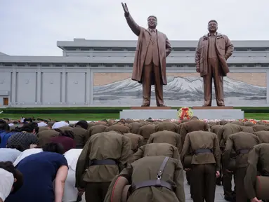 Tentara Rakyat Korea membungkuk di depan patung pemimpin Korea Utara, Kim Il Sung dan Kim Jong Il di Bukit Mansu, Pyongyang, pada peringatan 24 tahun kematian Kim Il Sung, Minggu (8/7). Kim Il-sung memimpin Korut sejak 1948 hingga 1994. (AFP/KIM Won-Jin)