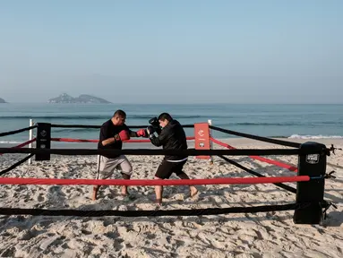  Pelatih tinju, Moacyr Lima (kiri), melatih Leandro Guignoni di ring tinju yang terletak di Pantai Pepe, Rio de Janeiro, Brasil, (26/7/2016). (AFP/Yasuyoshi Chiba)