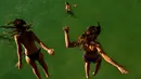 Dua wanita melompat ke air di pantai La Concha saat musim panas di kota basque San Sebastian, Spanyol (3/8).  Udara panas dari Afrika membawa gelombang panas ke Eropa, mendorong peringatan kesehatan tentang debu Sahara Desert. (AP Photo/Alvaro Barrientos)