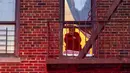 Seorang wanita melihat lokasi kebakaran gedung apartemen dari jendela di Bronx, New York, Amerika Serikat, 9 Januari 2022. Menurut Komisaris FDNY Daniel Nigro, mayoritas korban tewas karena menghirup asap yang parah. (AP Photo/Jeenah Moon)