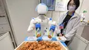 Sebuah robot menyortir dan menempatkan potongan ayam goreng ke dalam wadah. (Richard A. Brooks/AFP)