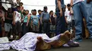 Dalam gambar yang diambil pada 10 November 2016, warga dan polisi berkumpul dekat jasad seorang wanita paruh baya berusia 47 tahun yang tewas ditembak oleh orang tak dikenal dalam perang melawan narkoba di Manila, Filipina. (TED Aljibe/AFP)