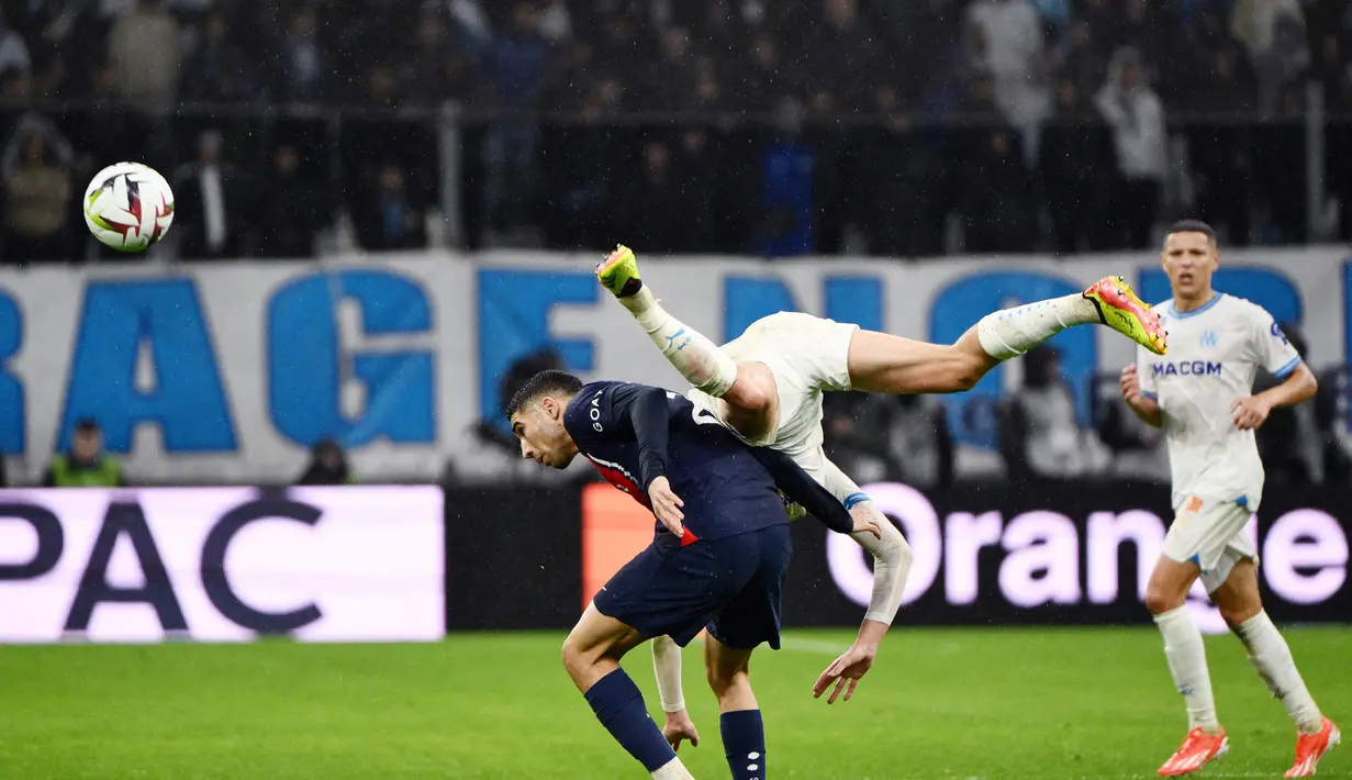Pemain Paris Saint-Germain, Achraf Hakimi, berebut bola dengan pemain Marseille dalam laga pekan ke-27 Ligue 1 2023/2024 di Stade Velodrome, Senin (1/4/2024). (AFP/Christophe Simon)