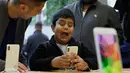Seorang anak bermain fitur animoji iPhone X di toko Apple Union Square di San Francisco (3/11). iPhone X juga memiliki fitur terbaru Face ID yang berfungsi mendeteksi dan mengenali wajah pemilik sebagai kunci membuka perangkat. (AP Photo/Eric Risberg)
