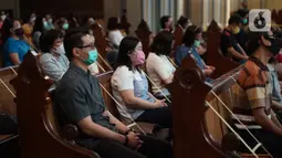 Jemaat duduk di antara pembatas jarak tubuh saat melaksanakan ibadah misa di Gereja Katedral Jakarta, Minggu (12/7/2020). Gereja Katedral Jakarta kembali menggelar misa bagi umat Katolik dengan menerapkan protokol kesehatan untuk mencegah penularan Covid-19. (Liputan6.com/Immanuel Antonius)