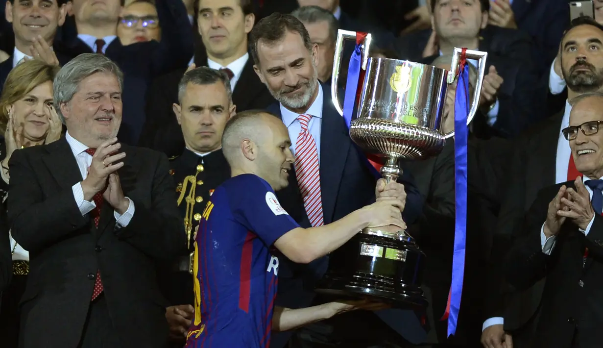 Gelandang Barcelona, Andres Iniesta, menerima trofi Piala Raja Spanyol di Stadion Wanda Metropolitano, Madrid, Sabtu (21/4/2018). Sebanyak enam gelar Piala Raja Spanyol diraihnya bersama La Blaugrana. (AFP/Cristina Quicler)
