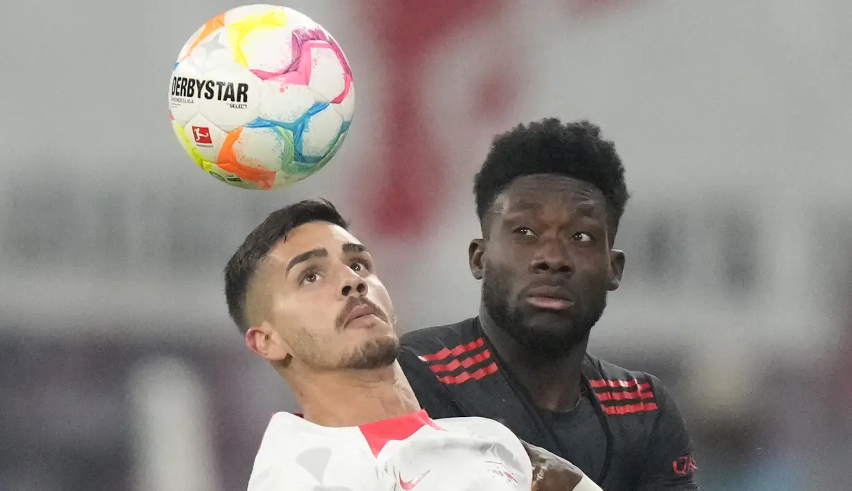 Penyerang RB Leipzig Andre Silva melakukan sundulan dengan gelandang Bayern Munchen  Alphonso Davies pada laga pekan ke-16 Bundesliga Jerman 2022-2023 di Red Bull Arena, Sabtu (21/1/2023) dini hari WIB.  RB Leipzig berhasil tahan imbang Bayern Munchen dengan skor 1-1. (AP Photo/Matthias Schrader)