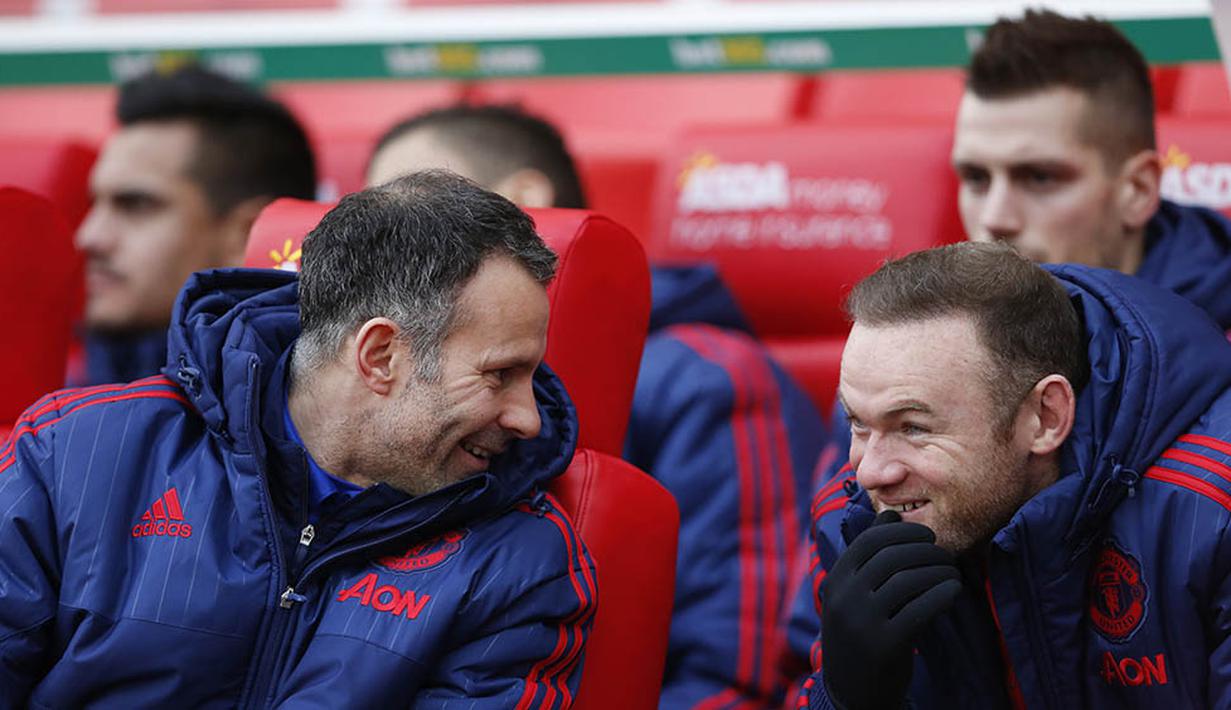 Asisten pelatih MU, Ryan Giggs tertawa bersama Wayne Rooney saat berada di bangku cadangan kala MU bertanding melawan Stoke. (Reuters/Carl Recine)