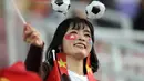 Suporter Timnas Indonesia dan Vietnam sama-sama mengenakan aksesoris senada dengan warna bendera negara mereka saat menyaksikan timnya bertanding. (KARIM JAAFAR/AFP)