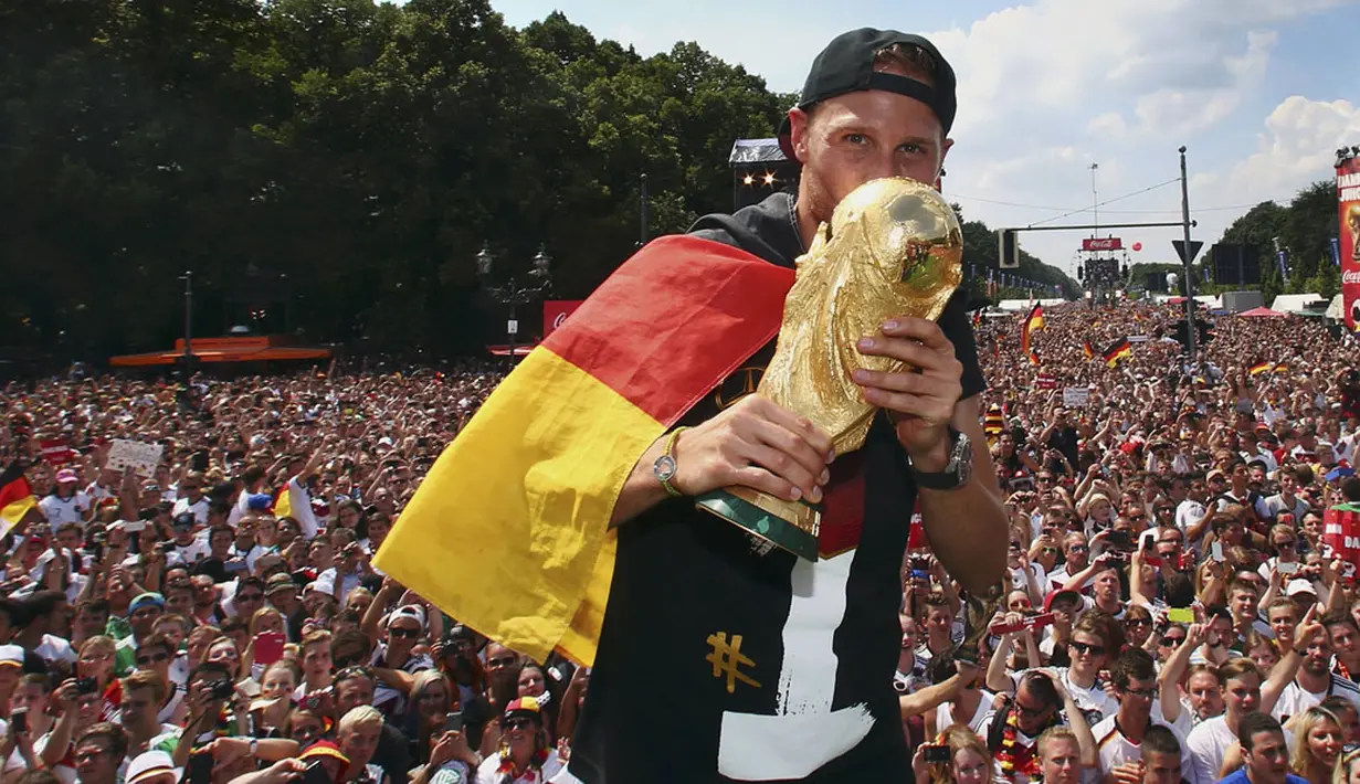 Pemain belakang Timnas Jerman, Benedikt Hoewedes, mencium trofi Piala Dunia saat perayaan kemenangan Der Panzer di Berlin, (15/7/2014). (REUTERS/Alex Grimm/Pool) 