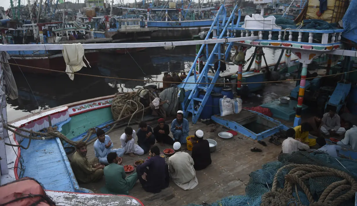 Nelayan duduk di atas kapal saat mereka berdoa sebelum berbuka puasa selama bulan suci Ramadhan di galangan kapal di kota pelabuhan Karachi, Pakistan pada 18 April 2022. Setelah menjalani ibadah puasa, waktu buka puasa menjadi momen yang dinanti oleh umat Islam. (Rizwan TABASSUM / AFP)