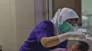 Perawat merapikan rambut seorang bayi setelah dimandikan saat kegiatan pelatihan di RSIA Tambak, Jakarta, Kamis (18/02/2021). Melatih para ibu baru untuk memandikan bayi pertama tersebut dilakukan dengan menerapkan protokol kesehatan ketat. (Liputan6.com/Herman Zakharia)