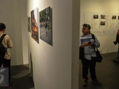 Seorang pengunjung melihat pameran Anugerah Pewarta Foto Indonesia (APFI) 2017 di Jakarta, Jumat (21/4). Sebanyak 15 karya foto jurnalistik terbaik telah dipilih dari 5.488 karya foto yang dikirimkan oleh 410 pewarta foto. (Liputan6.com/Faizal Fanani)