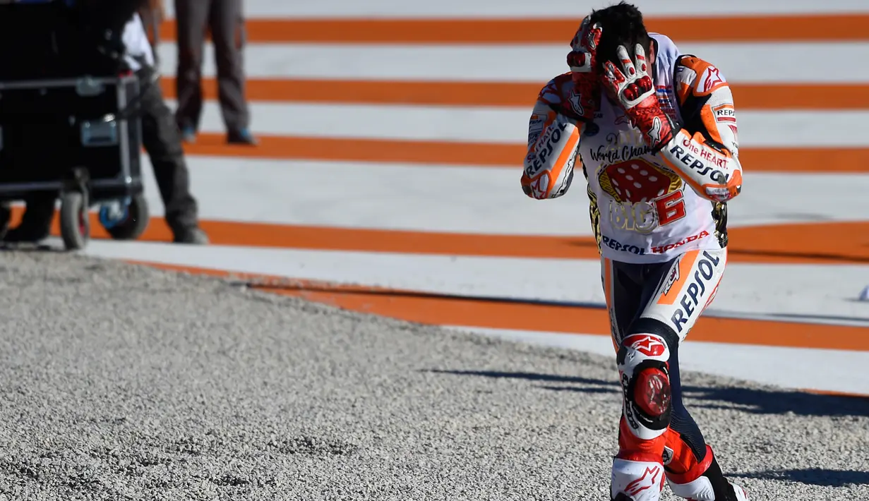 Pembalap Spanyol Repsol Honda, Marc Marquez meluapkan kegembiraannya sambil memegang kepala setelah memenangkan balapan seri ke 18 MotoGP Grand Prix Valencia di Sirkuit Ricardo Tormo, Valencia (12/11). (AFP PHOTO / Jose Jordan)