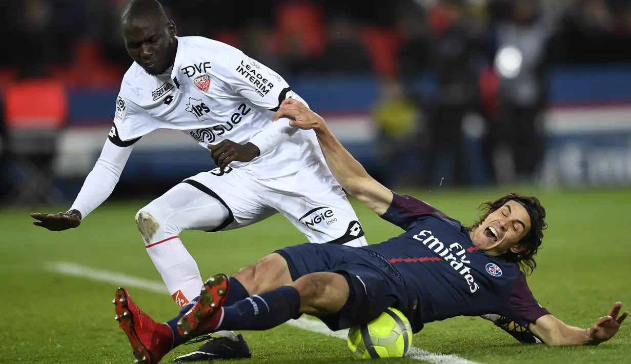 Pemain PSG, Edinson Cavani jatuh saat berebut bola dengan pemain Dijon, Cedric Yambere pada laga Ligue 1 di Parc des Princes stadium, Paris, (17/1/2018). PSG menang telak 8-0. (AFP/Christophe Simon)