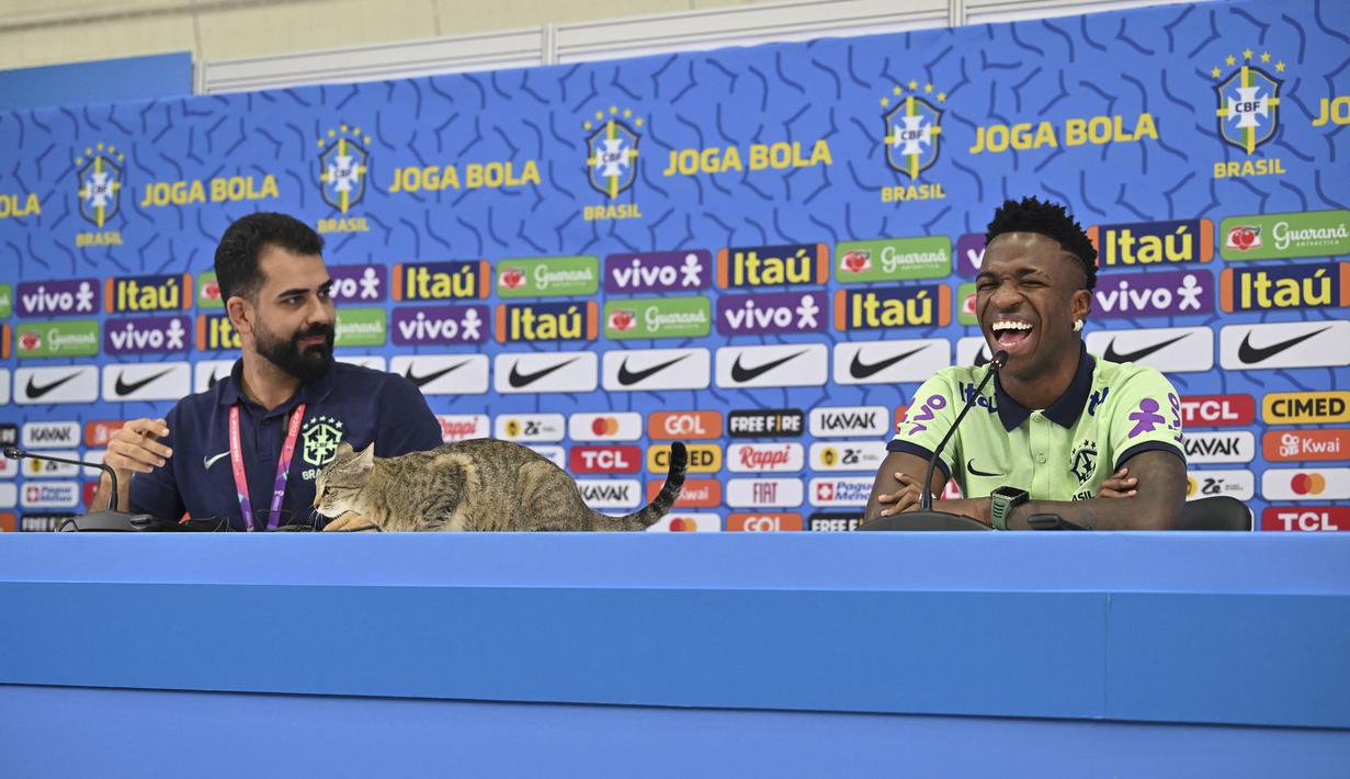 Ada seeokor kucing yang tiba-tiba menaiki meja yang ditempati Vinicius Junior dan staf media Timnas Brasil. (AFP/Nelson Almeida)