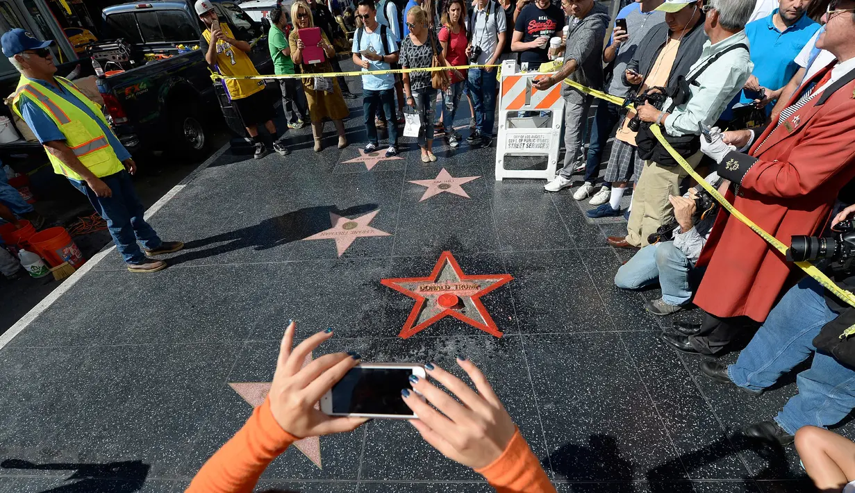 Warga melihat perbaikan Hollywood Walk of Fame milik Donald Trump usai dirusak seorang pria bernama James Lambert Otis , California, AS (26/10). Nama Donald Trump sendiri masuk kedalam daftar Walk of Fame pada tahun 2007. (David McNew/Getty Images/AFP)