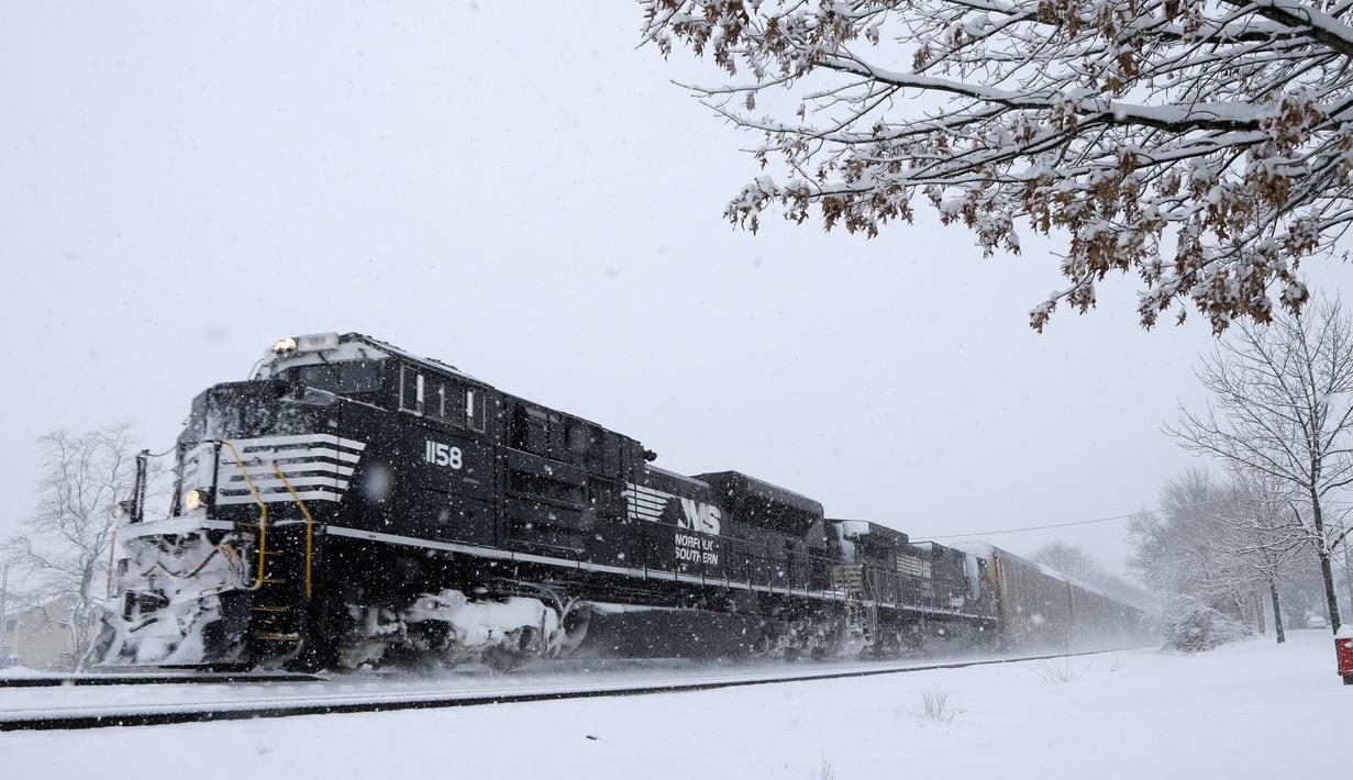 Sebuah kereta barang melaju saat badai salju di Manville, New Jersey (21/3). Badai salju yang melanda sebagian Amerika Serikat telah membawa salju dan angin kencang. (AP/Julio Cortez)