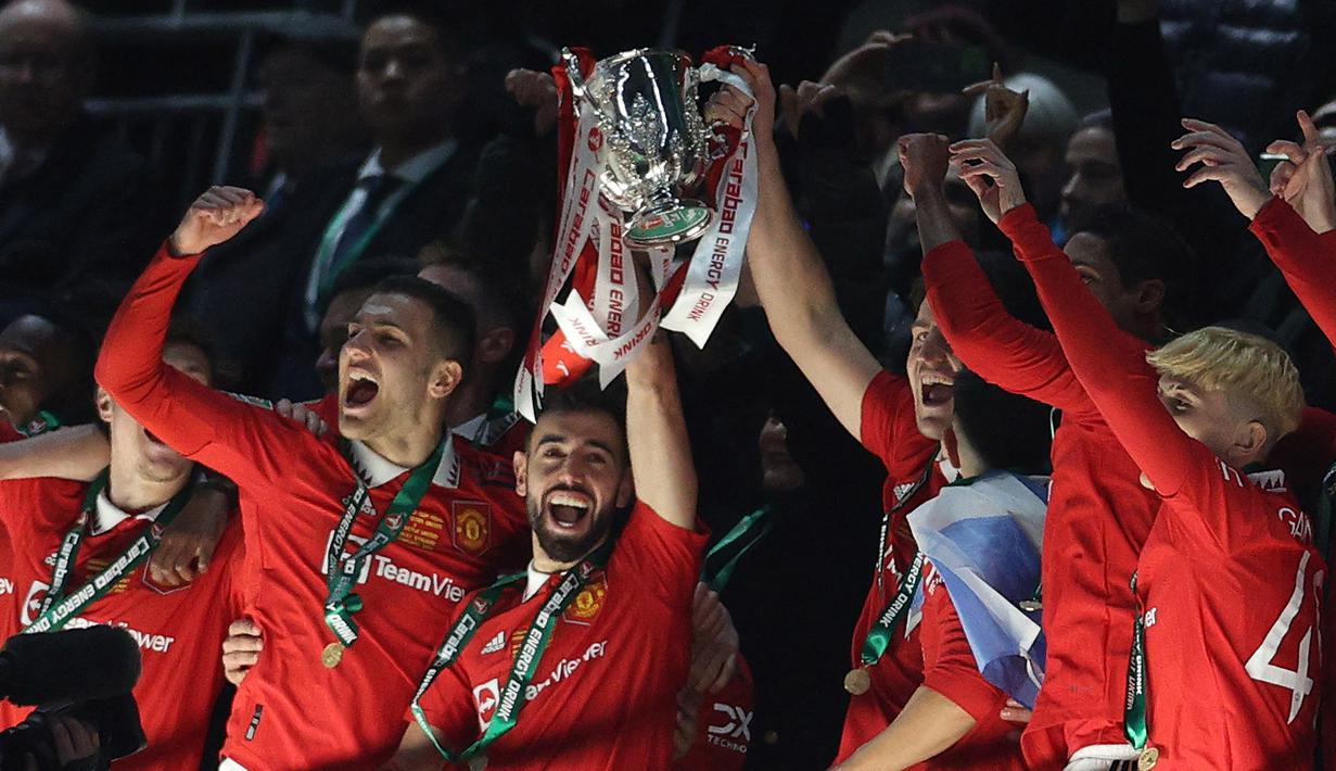 Pemain Manchester United, Bruno Fernandes mengangkat trofi setelah memenangkan final Carabao Cup 2023 melawan Newcastle United yang berlangsung di Wembley Stadium, Minggu (26/2/2023) waktu setempat. (AFP/Adrian Dennis)