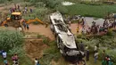 Warga dan polisi menyaksikan bus tingkat yang rusak usai mengalami kecelakaan di jalan bebas hambatan di Agra, India, Senin (8/7/2019). Sopir diduga mengantuk sehingga bus tersebut menabrak pembatas jalan Tol Yamuna dan terjun ke sungai di bawahnya. (Pawan Sharma/AFP)