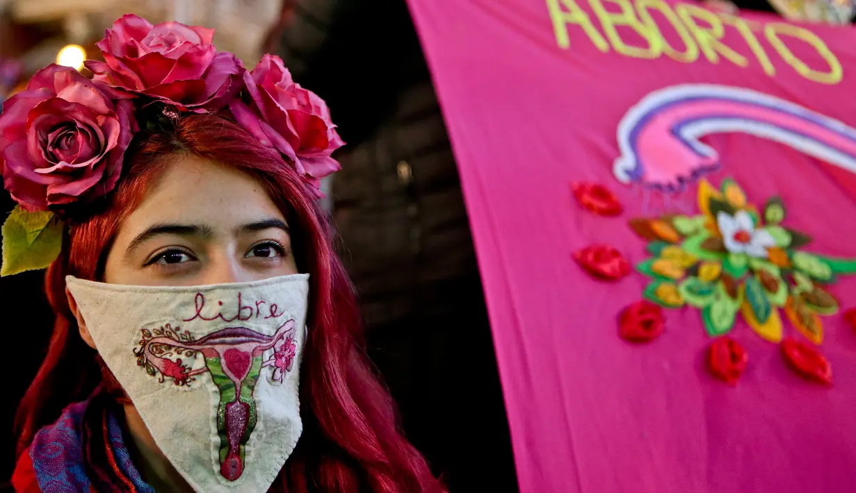 Seorang wanita menutupi wajahnya dengan saputangan saat aksi mendukung undang-undang untuk melegalkan aborsi di Santiago, Chile (25/7). Mereka menuntut untuk melegalkan aborsi dalam tiga situasi. (AP Photo/Esteban Felix)