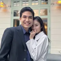 Nong Poy memamerkan cincin saat bersama calon suaminya. Dalam foto tersebut, ia mengenakan coat abu-abu dengan riasan wajah minimalis bahkan terlihat tanpa makeup. @poydtreechada.
