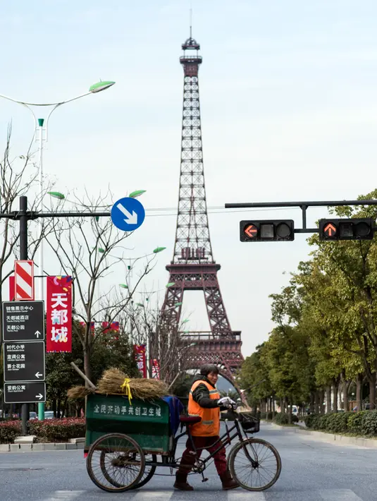 Warga melintas di depan replika Menara Eiffel di Tianducheng, pinggiran Hangzhou, China, 26 Januari 2016. Selain itu, di kawasan replika tersebut tersedia 10.000 rumah bergaya Eropa siap huni dan vila yang bisa disewakan. (AFP PHOTO/Johannes EISELE)