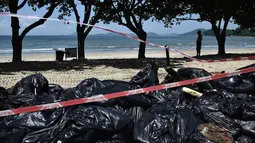 Tumpukan kantong plastik berisi sampah di tepi sebuah pantai di Hong Kong, Senin (7/8). Kecelakaan kapal pengangkut minyak sawit di perairan sekitar Hong Kong memaksa negara di bawah kedaulatan China itu menutup 10 pantainya. (Anthony WALLACE / AFP)