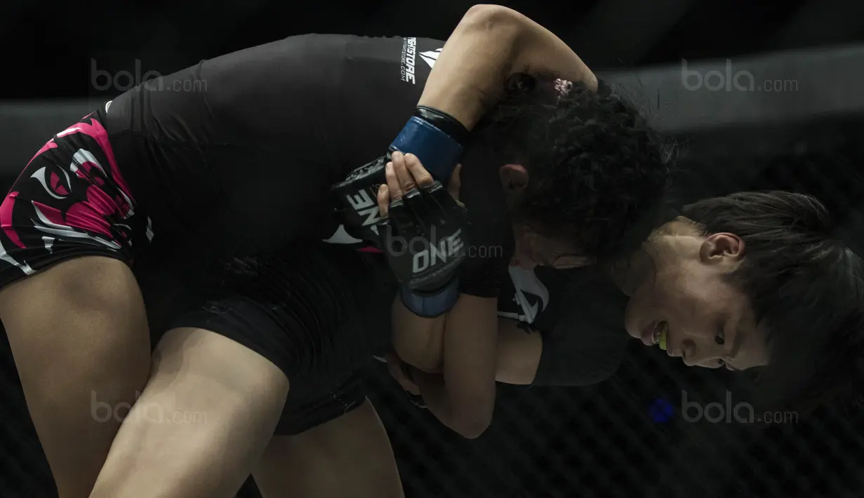 Petarung Cina, Xiong Jing Nan, mengunci petarung Singapura, Tiffany Teo, saat laga One Championship di JCC Senayan, Jakarta, Sabtu (20/1/2018). Jing Nan berhasil merebut juara dunia kelas jerami. (Bola.com/Vitalis Yogi Trisna)