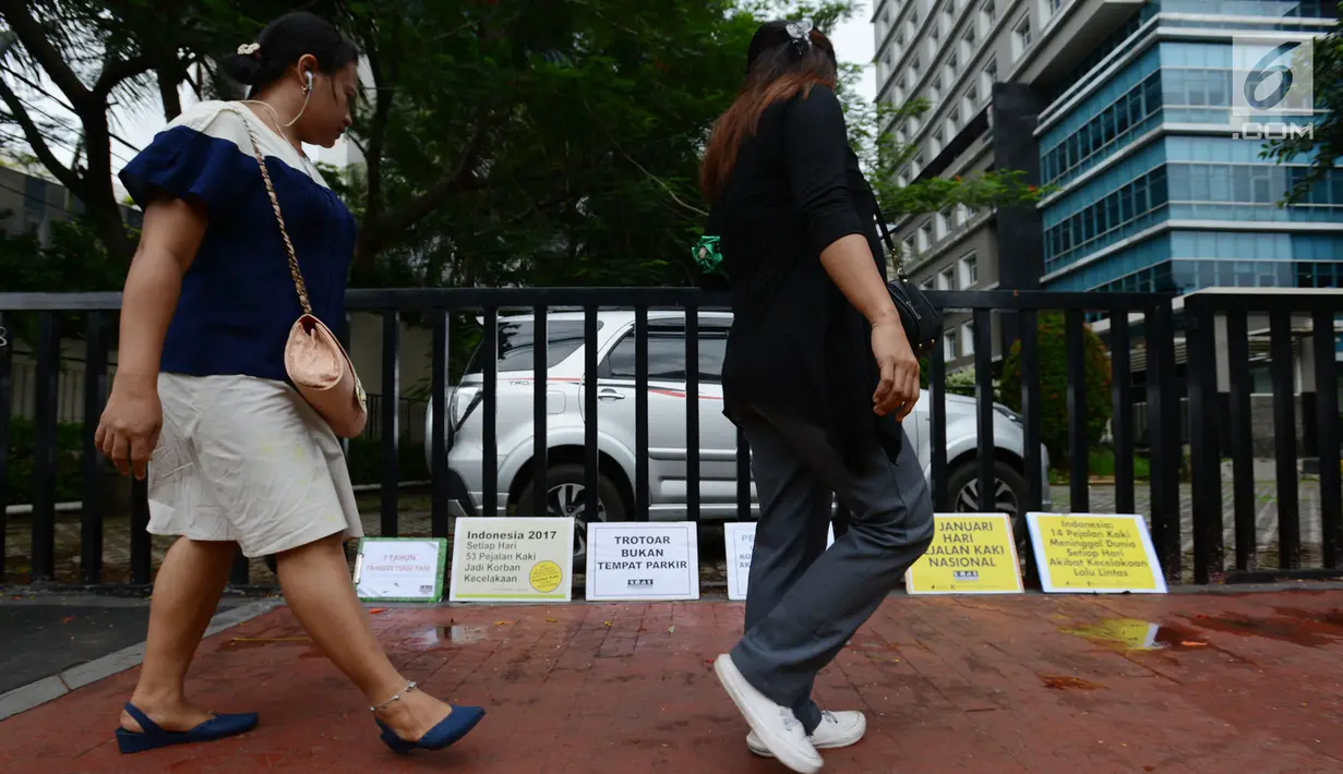 Warga melintasi poster yang diletakkan oleh aktivis Koalisi Pejalan Kaki saat berkampanye dalam rangka memperingati Hari Pejalan Kaki Nasional di kawasan Tugu Tani, Jakarta, Selasa, (22/1). (Merdeka.com/Imam Buhori)