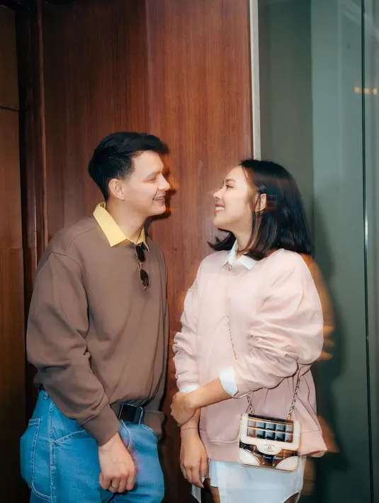 Manisnya potret Marcell Darwin dan sang istri di sini. Marcell tampil bergaya retro dengan kemeja oranye yang ditumpuknya dengan sweater cokelat, dan celana jeans. Sedangkan Nabila tampil cantik dengan oversized shirt berwarna putih yang ditumpuknya dengan sweater pink. [Foto: Instagram/marcelldarwin]