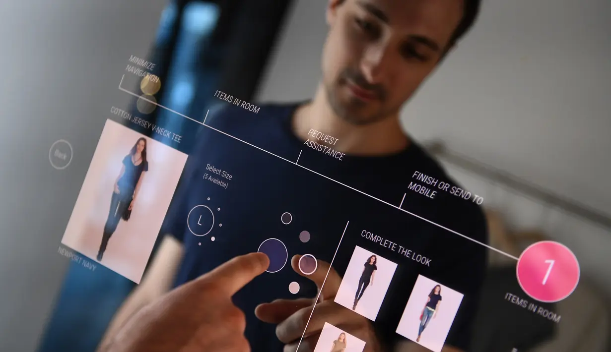 Peneliti Oak Labs, Wesley Bliss saat menggunakan cermin pintar Oak Fitting Room di sebuah butik, New York, AS (7/2). Cermin yang dilengkapi dengan teknologi RFID ini mampu mendeteksi baju yang dibawa pembeli. (AFP Photo / Jewel Samad)