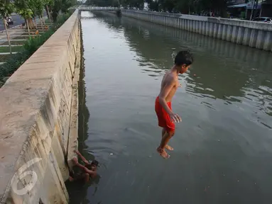 Seorang anak melompat ke anak Kali Ciliwung di Jakarta, Rabu (13/7). Bersihnya kali yang berada di Ibu Kota itu dimanfaatkan anak-anak sekitar untuk berenang sambil mengisi waktu libur sekolah. (Liputan6.com/Immanuel Antonius)