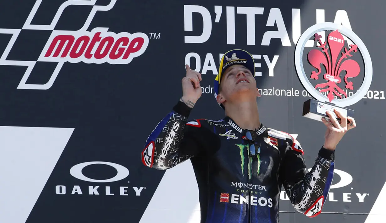 Pembalap Yamaha Fabio Quartararo melihat dan menunjuk ke langit selama upacara podium pada akhir Motogp Mugello di Sirkuit Mugello, Scarperia, Italia, Minggu (30/5/2021). Fabio Quartararo berhasil meraih posisi pertama. (AP Photo/Antonio Calanni)