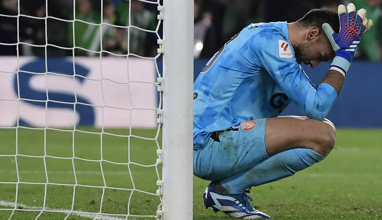 Reaksi kecewa kiper Girona, Paulo Gazzaniga setelah gawangnya dibobol oleh pemain Real Betis, German Pezzella pada laga pekan ke-18 Liga Spanyol 2023/2024 di Benito Villamarin Stadium, Sevilla, Spanyol, Jumat (22/12/2023) dini hari WIB. (AFP/Cristina Quicler)