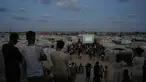 Warga Palestina menyaksikan siaran langsung pertandingan sepak bola Piala Dunia antara Spanyol dan Arab Saudi melalui layer lebar di Nuseirat, Jalur Gaza Tengah, Minggu 21 Juni 2026. (AP Photo/Abdel Kareem Hana)