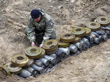Seorang pencari ranjau Kementerian Dalam Negeri menyiapkan bahan peledak pada sebuah lubang untuk meledakkannya dekat ladang ranjau setelah pertempuran baru-baru ini di Desa Moshchun, dekat Kyiv, Ukraina, 19 April 2022. (AP Photo/Efrem Lukatsky)