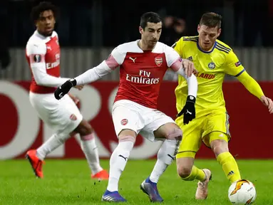 Gelandang Arsenal, Henrikh Mkhitaryan berebut bola dengan pemain BATE Borisov, Maksim Skavysh pada leg pertama 32 besar Liga Europa di Borisov Arena, Kamis (14/2). Arsenal kalah dengan skor 0-1 saat bertandang ke markas Bate Borisov. (AP/Sergei Grits)