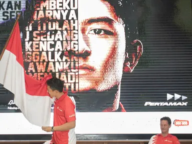 Rio Haryanto mencium bendera merah putih yang dipegang Menpora Imam Nahrawi sesaat setelah resmi diumumkan sebagai pebalap F1 bersama tim Manor Racing di kantor pusat Pertamina, Jakarta, Kamis (18/2/2016). (Bola.com/Vitalis Yogi Trisna)