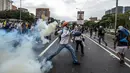 Demonstran melempar gas air mata yang telah ditembakkan polisi saat aksi menentang Presiden Venezuela Nicolas Maduro di Caracas, kamis (20/4). Tiga orang dikabarkan tewas dalam aksi demonstrasi tersebut.  (AFP PHOTO/ Juan BARRETO)