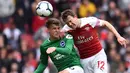 Gelandang Brighton, Solly March, duel udara dengan bek Arsenal, Stephen Lichtsteiner, pada laga Premier League di Stadion Emirates, London, Minggu (5/5) Kedua klub bermain imbang 1-1. (AFP/Glyn Kirk)