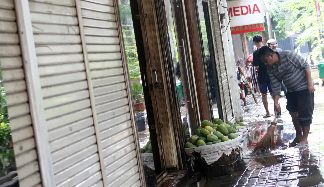Pedagang buah menyapu sekitar lokasi tempat berdagang di depan pertokoan Pasar Baru, Jakarta, Kamis (2/1/2020). Pasca banjir yang melanda sejumlah titik di Jakarta pada Rabu (1/1), aktivitas perniagaan di kawasan Pasar Baru masih sepi dan sebagian toko masih tutup. (Liputan6.com/Helmi Fithriansyah)
