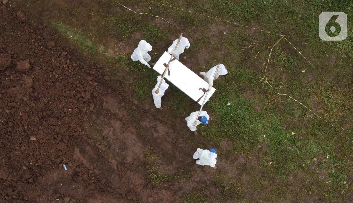 Foto udara petugas membawa peti jenazah dengan protokol COVID-19 di TPU Srengseng Sawah, Jakarta, Kamis (21/1/2021). Sebagian lahan TPU Srengseng Sawah yang dijadikan lokasi pemakaman jenazah Covid-19 sejak Selasa (12/1) lalu, kini hanya tersisa 79 petak makam. (Liputan6.com/Helmi Fithriansyah)
