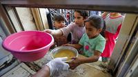 Anak-anak yang membutuhkan menerima makanan berbuka puasa dari juru masak di dapur Masjid Muslim Sunni Abdel Kader al-Kilani, Baghdad, Irak, 19 April 2021. Kegiatan ini berlangsung selama bulan suci Ramadhan. (AHMAD AL-RUBAYE/AFP)