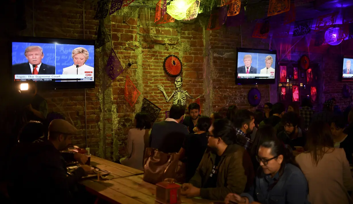 Pendukung Partai Demokrat terlihat serius menyaksikan debat Capres AS Donald Trump dan Hillary Clinton di Sebuah Restoran di Meksiko, (19/10). Debat kali ini menjadi pertarungan terakhir keduanya jelang Pemilu di AS. (AFP Photo/Yuri Cortez)