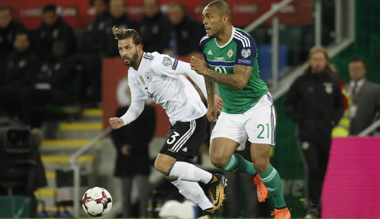 Striker Irlandia Utara, Josh Magennis, berusaha melewati bek Jerman, Marvin Plattenhardt, pada laga Kualifikasi Piala Dunia 2018 di Stadion Windsor Park, Kamis (5/10/2017). Jerman menang 3-1 atas Irlandia Utara. (AP/Peter Morrison)