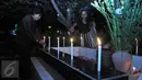 Warga menabur bunga dan menyalakan lilin saat ziarah ke makam yang terdapat di sebelah Gereja Tugu, Jakarta, Kamis (24/12). Tradisi tersebut dilakukan usai mengikuti ibadah kebaktian malam Natal di gereja. (Liputan6.com/Gempur M Surya)