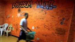 Pasien rehabilitasi membawa pakaian saat melintas di depan tembok bertuliskan "Freedom Wall" di Pusat Pemulihan Kristen di Antipolo, Filipina (12/9). (REUTERS/Romeo Ranoco)